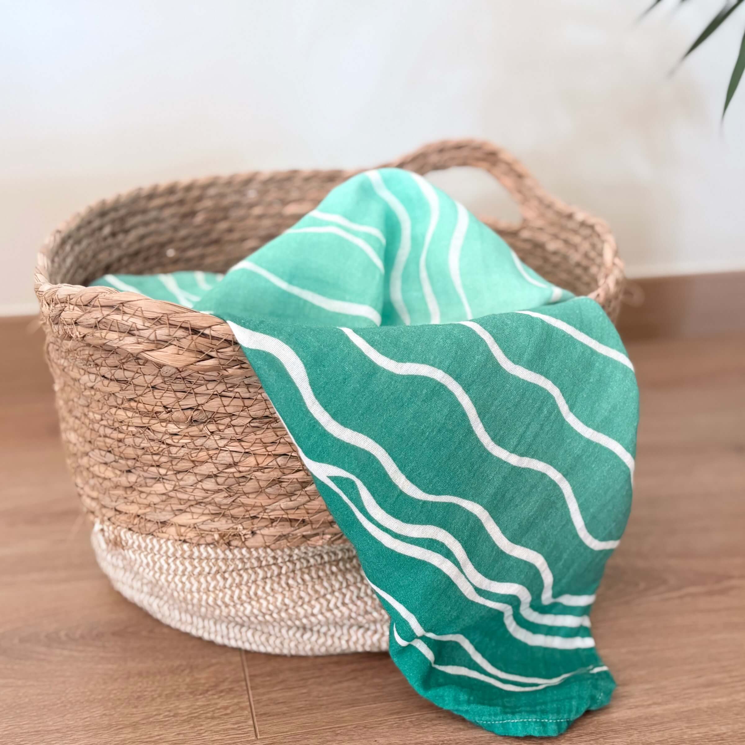 The Large Square Brisa do Mar with white waves draped over a woven basket on a wooden surface.