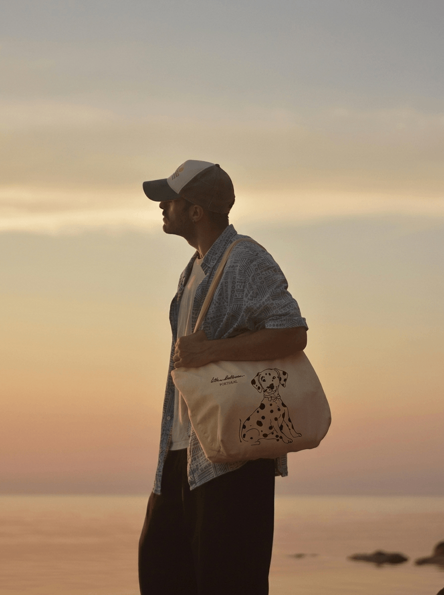 Man holding a tote bag with a sunset in the background