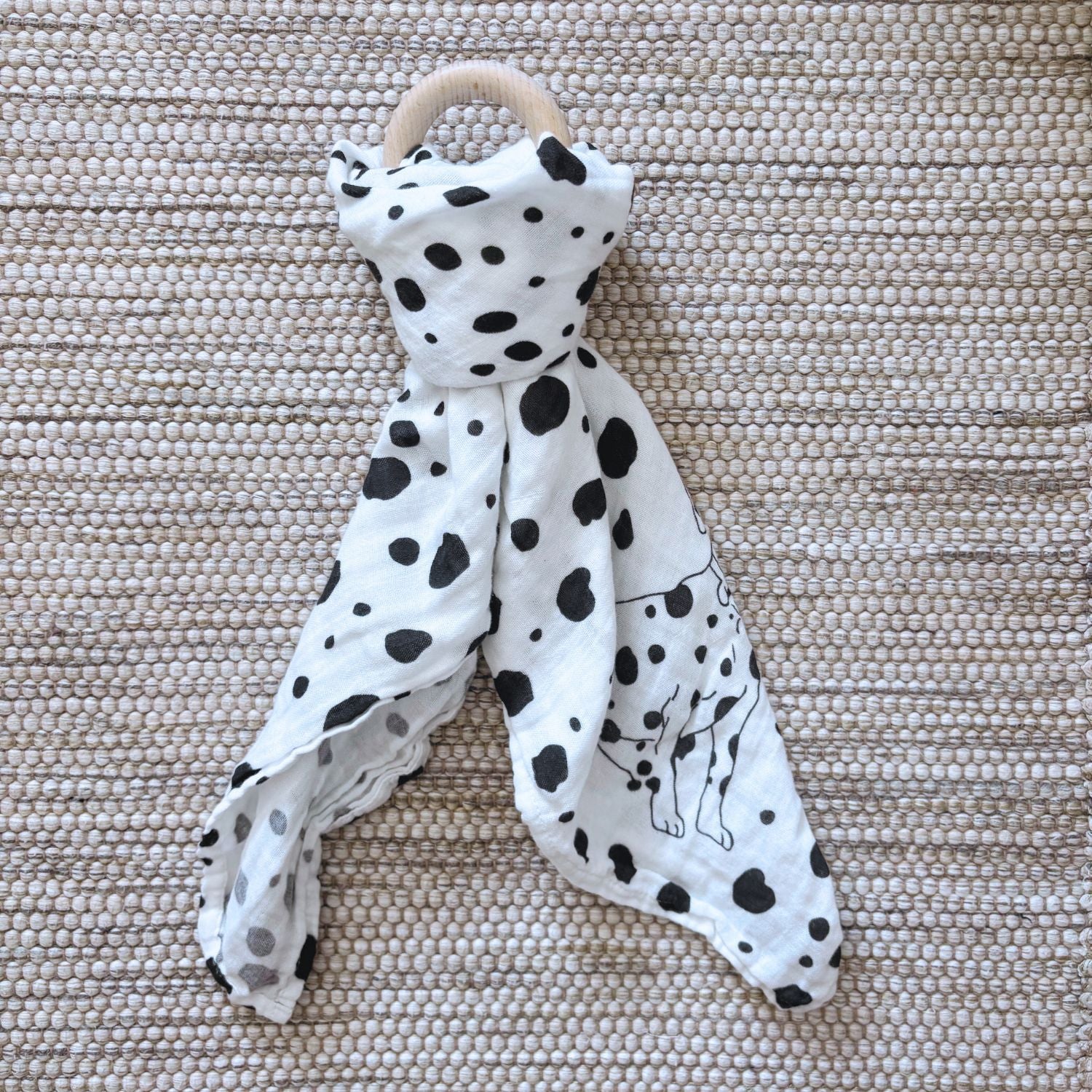 The Small Square muslin tied in a knot around a baby teether, demonstrating versatility beyond swaddling, its also great for play.