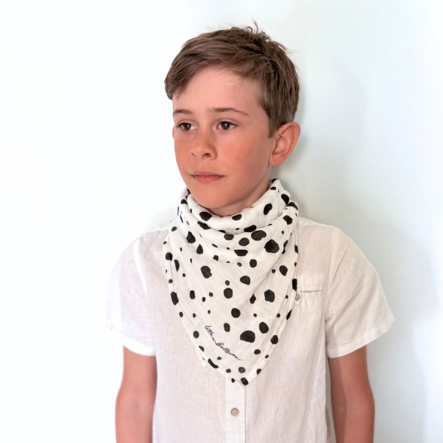 A boy wearing the Small Square muslin as a bandana neck scarf, demonstrating continued use as the child grows.