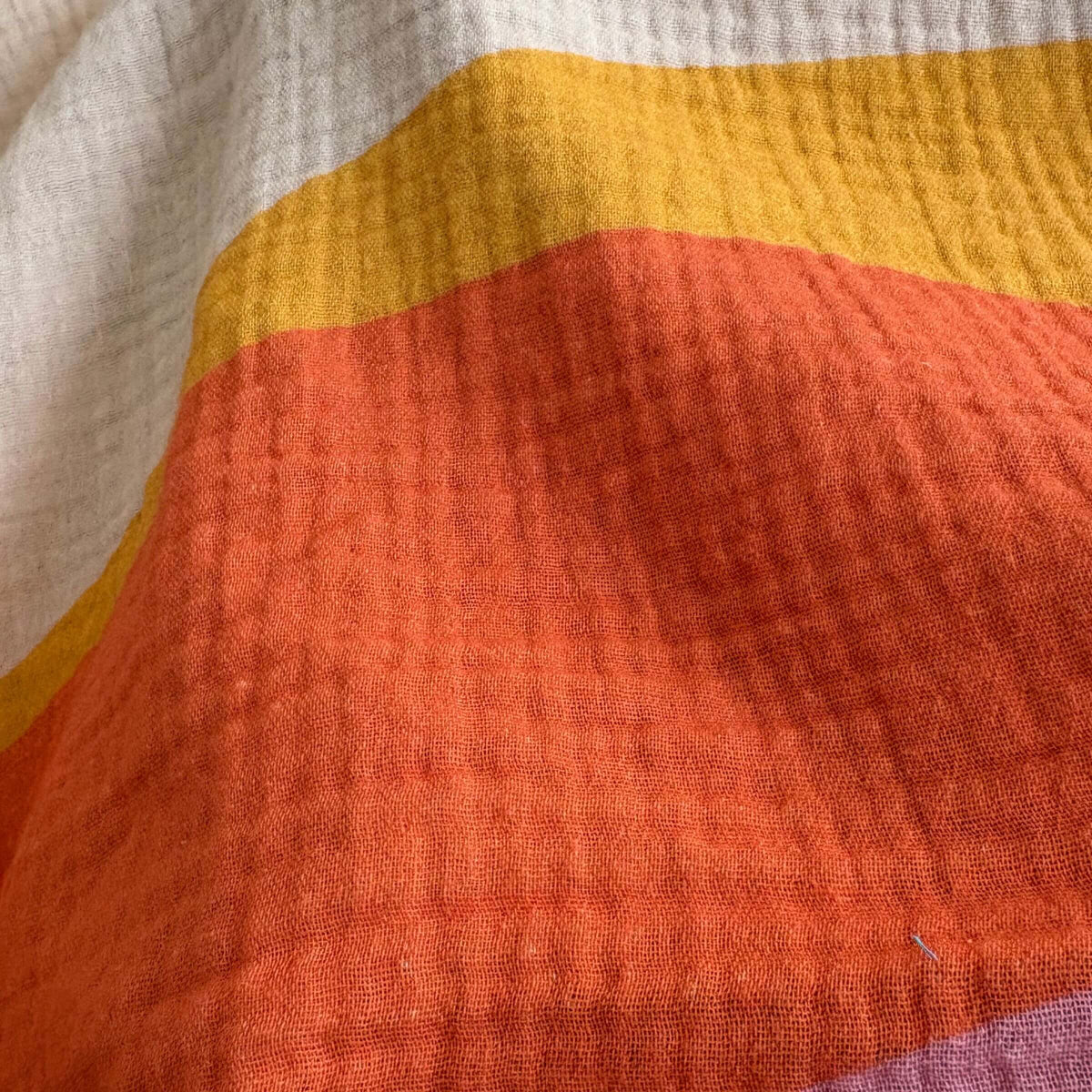 Close‑up view of the Indra Small Square muslin fabric, highlighting breathable cotton weave and flowing wave pattern.