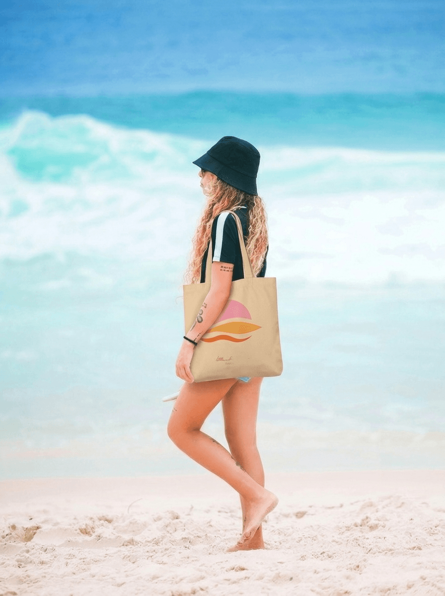 Woman walking on a beach with a tote bag and sun hat
