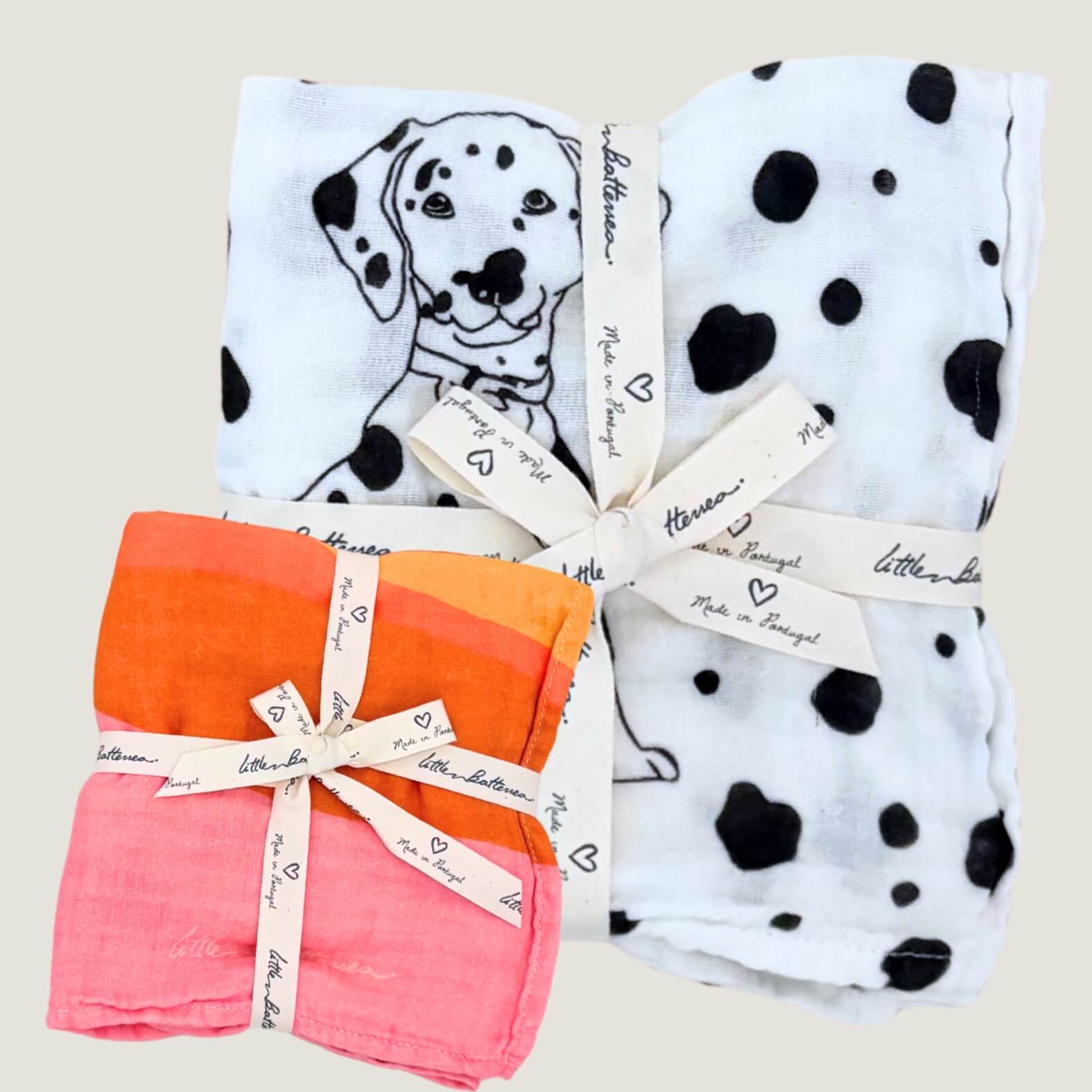 One baby blanket with Allure en Noir Dalmatian pattern and one baby muslin in Golden Indra design on a light background