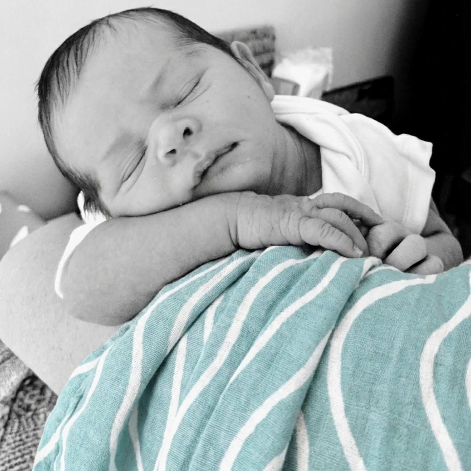 A newborn resting with the Brisa do Mar Small Square muslin nearby, showing comfort and softness in early days.