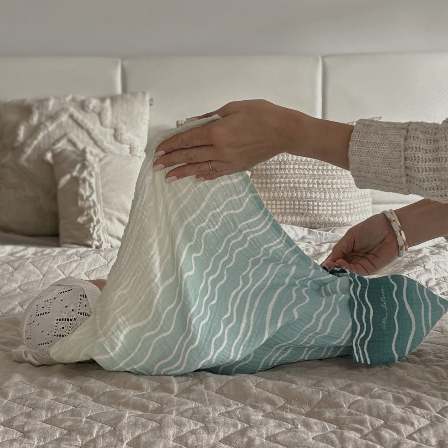 Person arranging pillows on a bed with a neutral color scheme