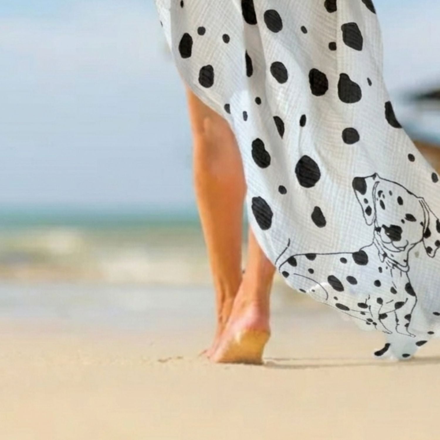Person wearing a Large squrae Allure en noir design as aa sarong on the beach. 
